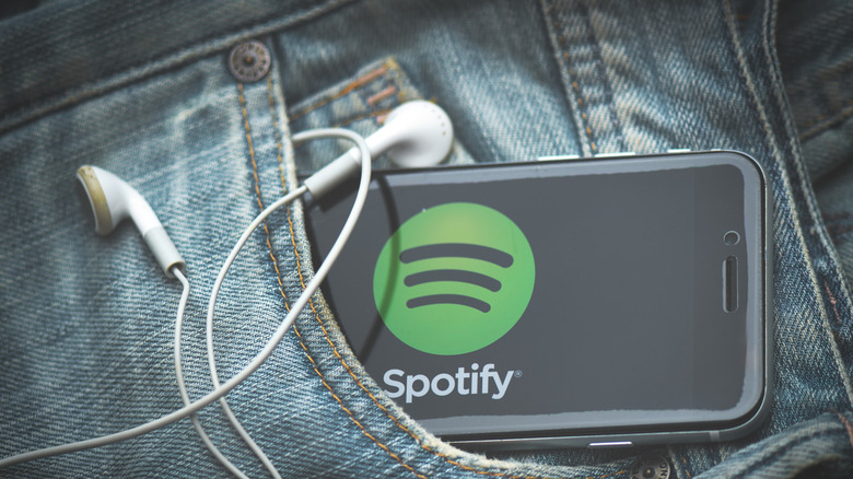 Spotify logo displayed on a smartphone inside a jeans pocket