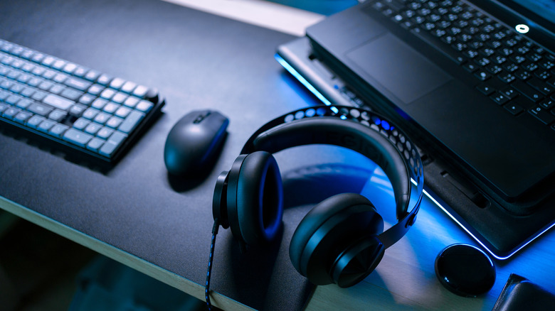 Modern gaming gear setup with laptop, wireless mouse, keyboard and headphone on a desktop