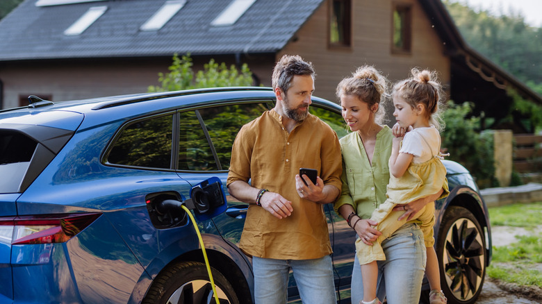 Family standing in front of a charging EV