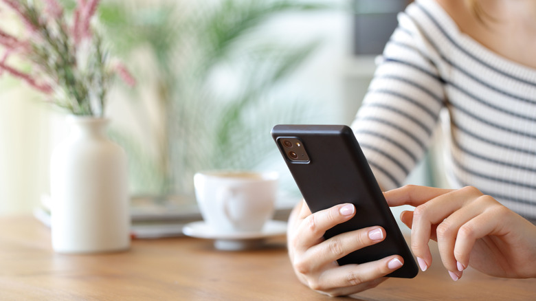 A woman looking at her phone while sitting at a table