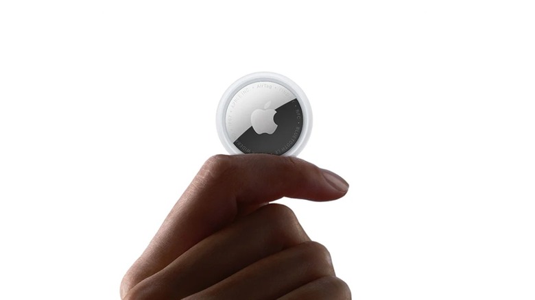 A person holding an Apple Air Tag (2nd Gen).