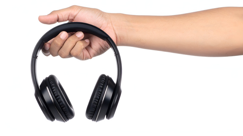 a hand holding a pair of headphones