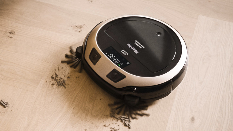 The Miele RX 3 Home Vision robot vacuum clearing mud on a hardwood floor.