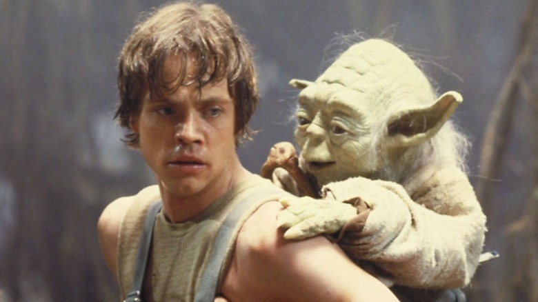 Luke Skywalker (Mark Hamill) holding Yoda in a backpack in The Empire Strikes Back