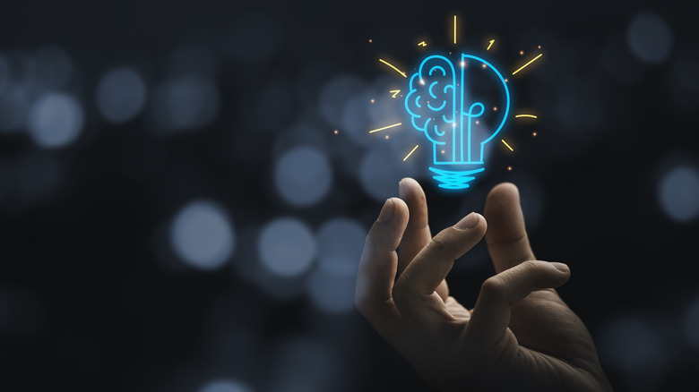 Person's hand and a graphic of a brain lightbulb hybrid.