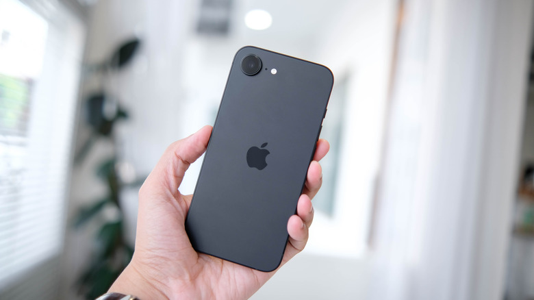 A black iPhone 16 being held in a hand.
