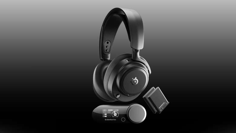 A pair of black SteelSeries Arctis Nova Pro Omni headphones with wireless hub and two batteries on a black-to-white gradient background.