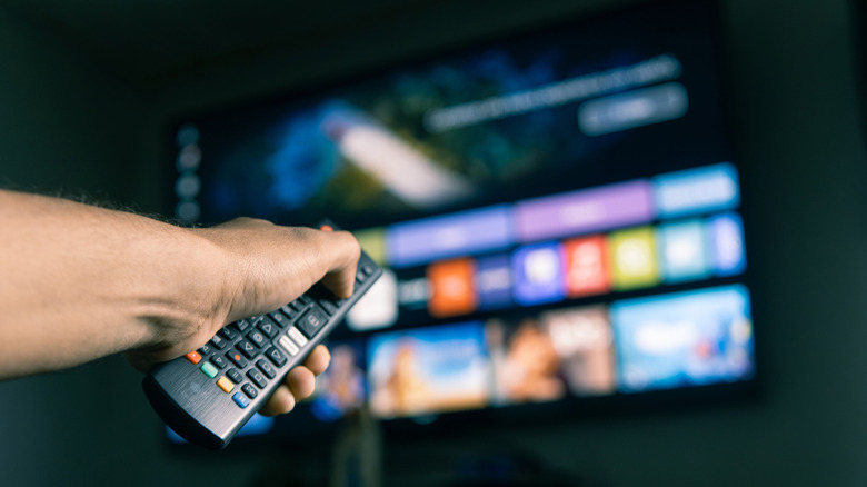 A person using a remote to control their T.V.
