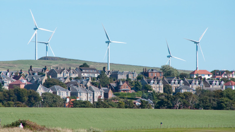 Wind turbines spin above a village