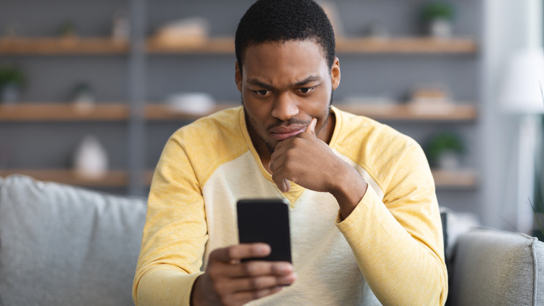 person looking at phone with a confused look