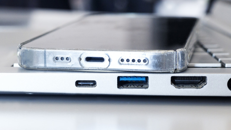 A phone sitting on an open laptop showing the multitude of charges on both devices