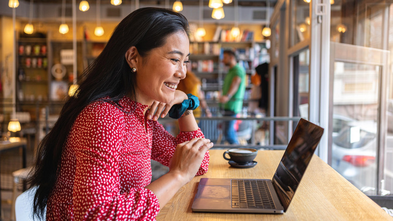 A woman having a video call via laptop, at a modern and cozy cafeteria