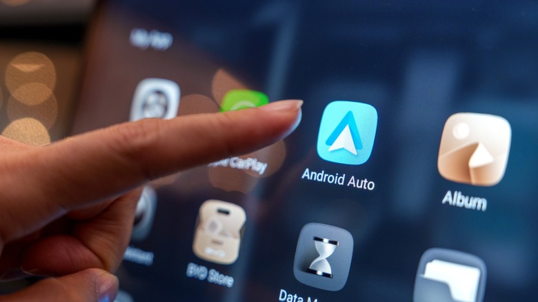 Person using finger to tapp Android Auto app on touchscreen