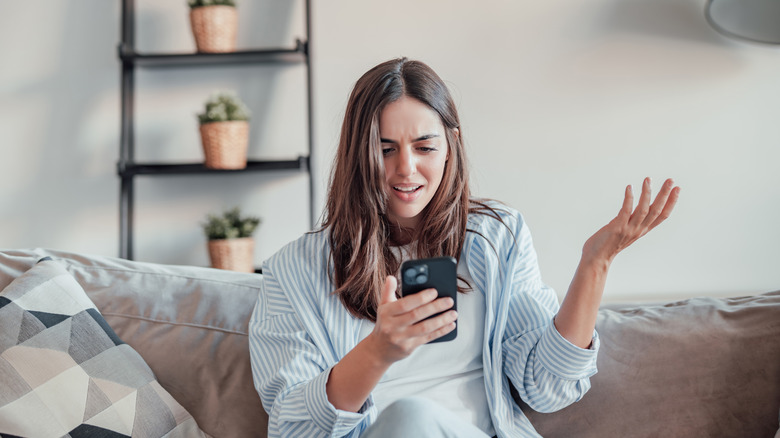 Woman on sofa frustrated with smartphone