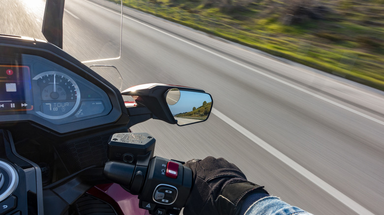 A motorcycle with a touchscreen display with the road blurring by in the background