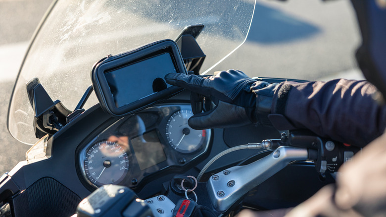 A motorcycle rider tapping the touchscreen on a dashboard