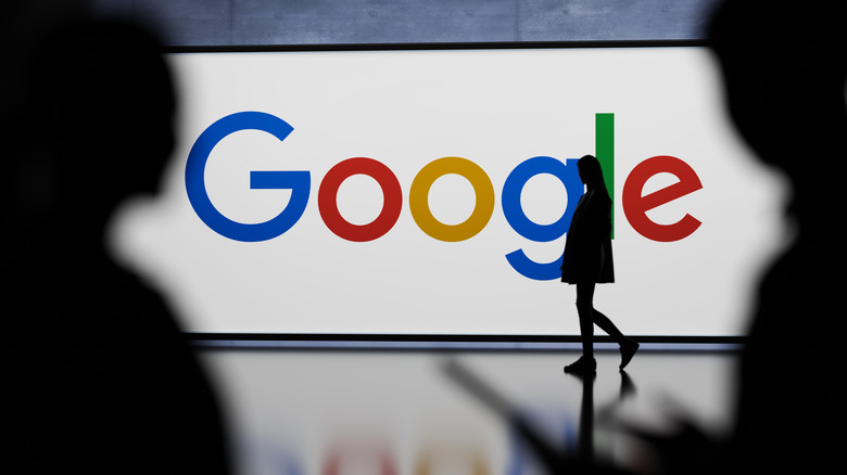 The Google logo on a billboard with a person walking in front of it.