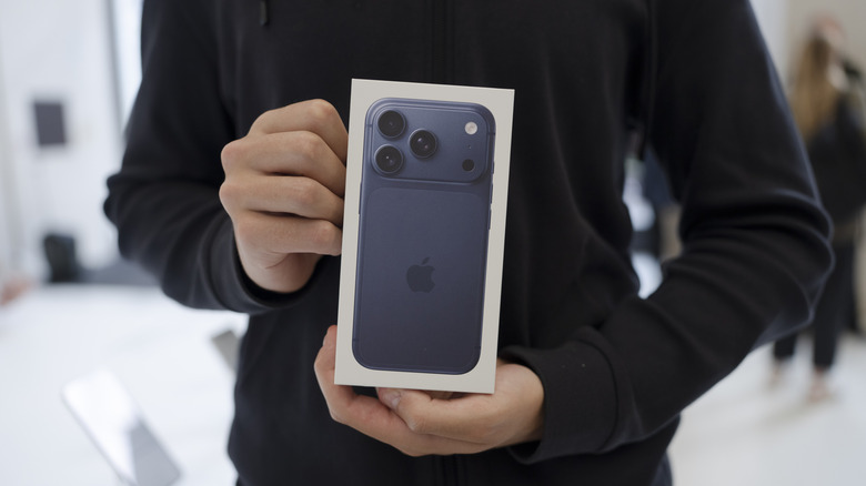 A person holding a iPhone 17 Pro retail box in a store.