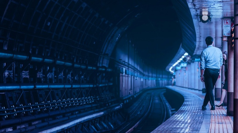 Blue lighting visible in a Japanese train station with passengers waiting.
