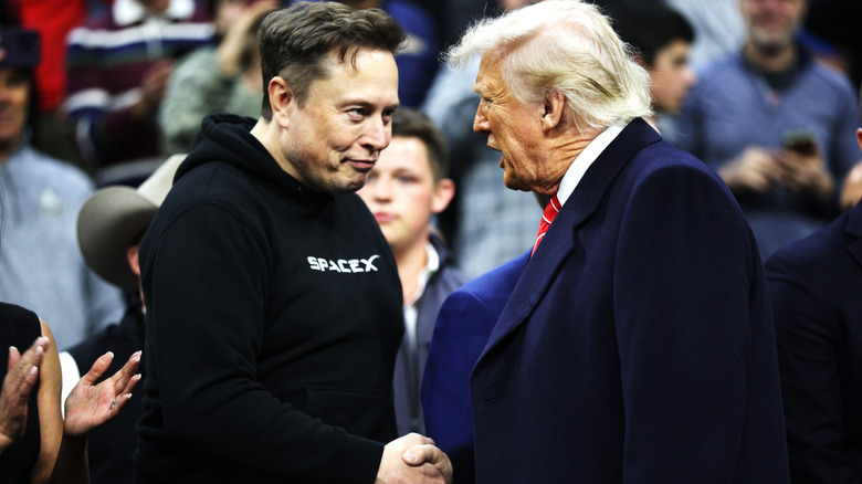 Elon Musk, wearing a SpaceX hoodie, shakes hands with U.S. President Donald Trump.