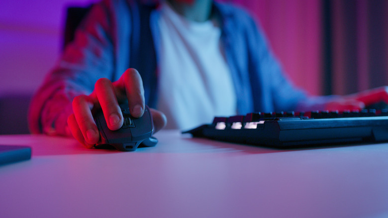 A person gaming with a wireless mouse next to their keyboard