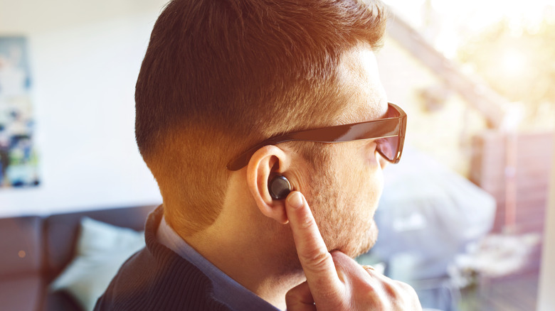 a man pointing to an earbud in one ear