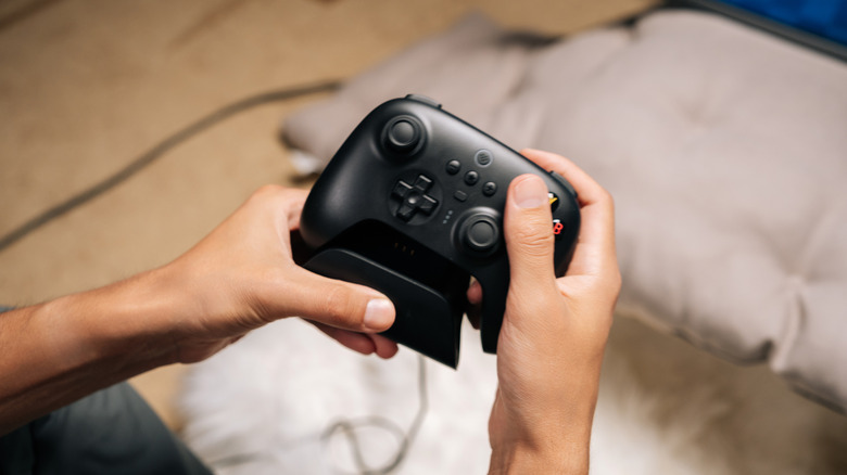 A person holding a modern, black wireless game controller.