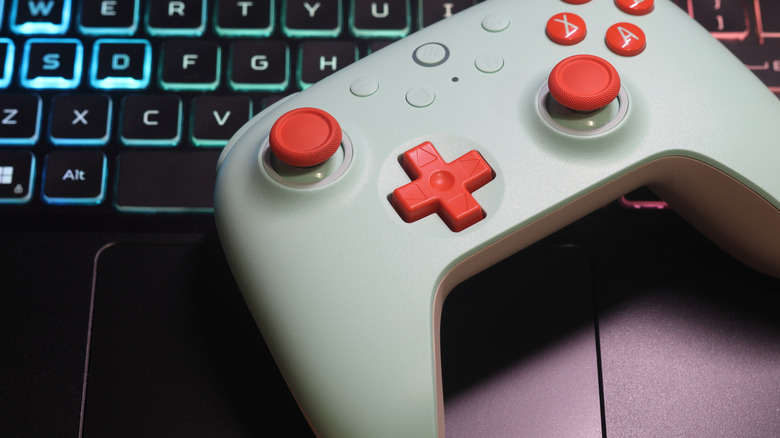 An 8BitDo wireless game controller placed on top of a laptop keyboard.
