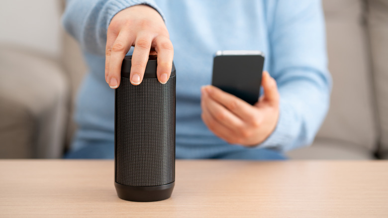 Closeup of a woman connecting a Bluetooth speaker to her phone