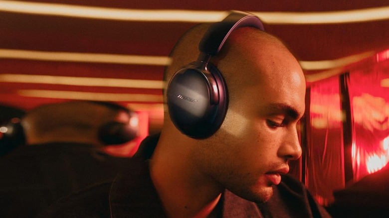 A person wearing the Bose QuietComfort Ultra Headphones in a dark indoor setting.
