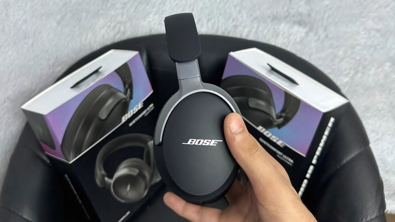 A person holding the Bose QuietComfort Ultra Headphones (2nd Gen) up above two product boxes.