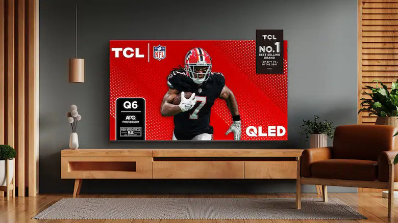 The TCL 98-inch Q6 Series QLED TV wall-mounted in a modern living room.