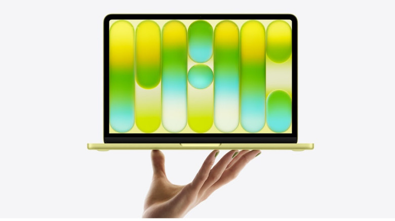MacBook Neo held in one hand with a colorful display.
