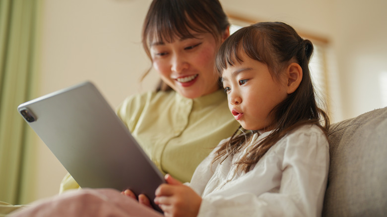 A mother and her young daughter engage with a tablet