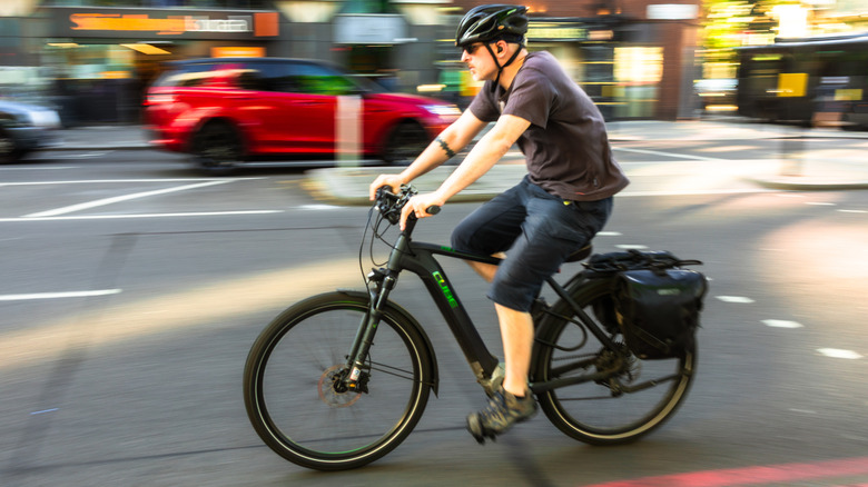 Rider driving fast with e-bike on city street with background a blur.