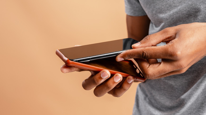 person inserting an iPhone into its orange silicone case
