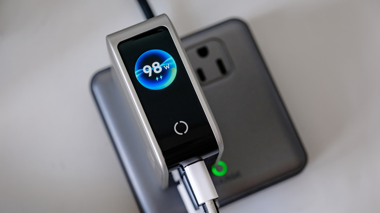 A UGREEN power adapter plugged into an AC outlet. A USB-C cable is plugged into the bottom of the adapter.