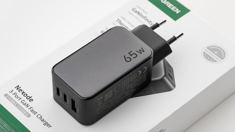 A UGREEN 65-watt USB-C power adapter placed on its product box.