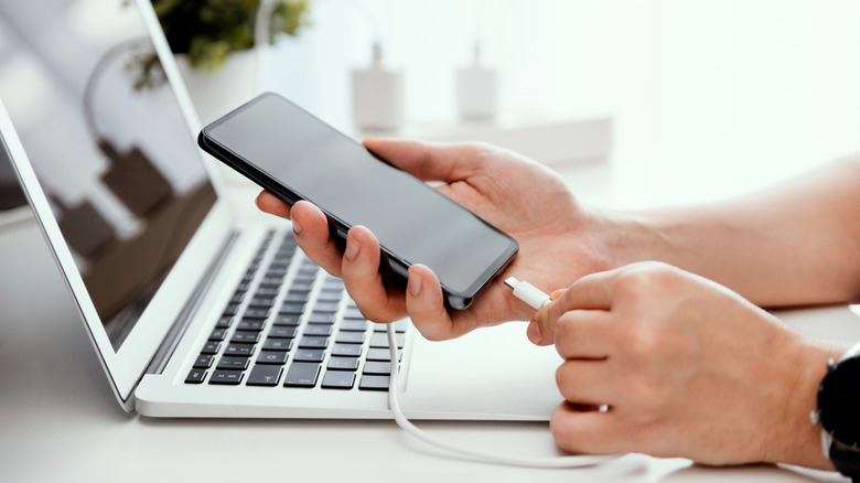 Close up of someone plugging a smartphone into a charger