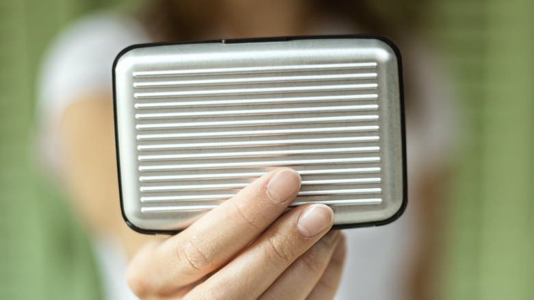 A person holding a metal RFID wallet