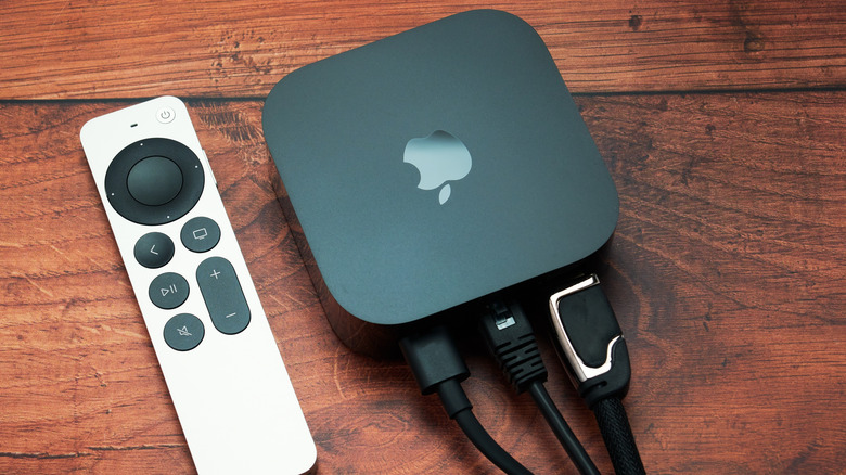 Apple TV 4K (2022) with Siri Remote on oak wood background with cables connected