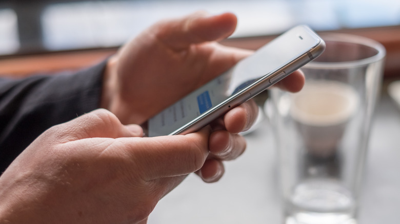 A side view of someone texting on an iPhone with the iMessage app visible.