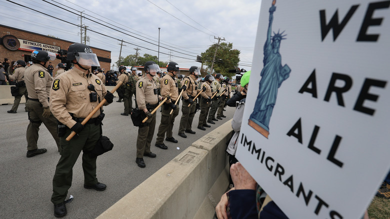 ICE protestors with a "we are all immigrants" sign face off against police