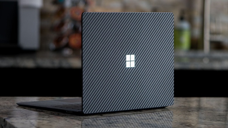 Laptop with black carbon fiber pattern vinyl wrap on kitchen countertop