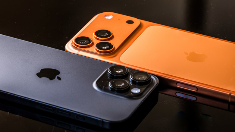 Two iPhones lying atop a black table