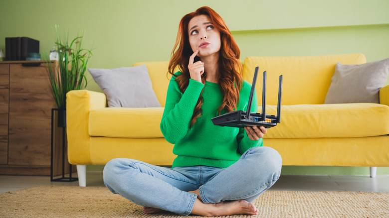 A woman sitting down holding a router and thinking