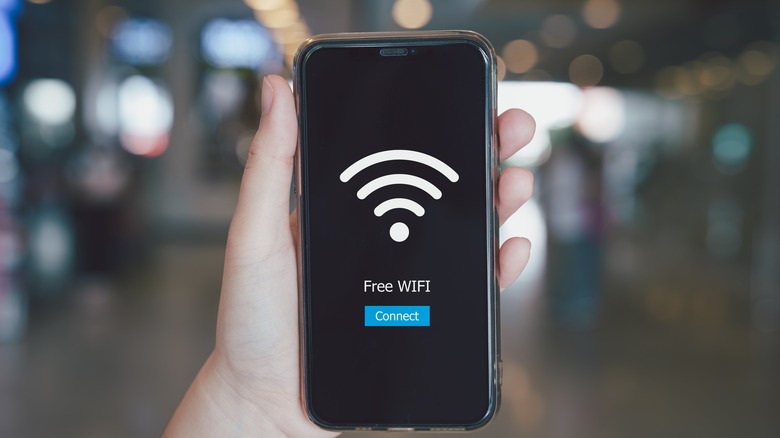 Person holding a smartphone with a wi-fi symbol with the words 