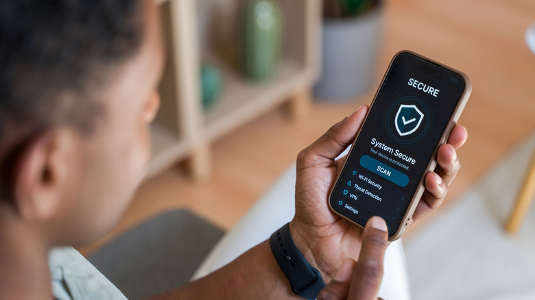 man looking at smartphone with secure checkmark status on display