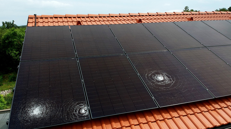 A rooftop solar panel with three large damage spots from hail
