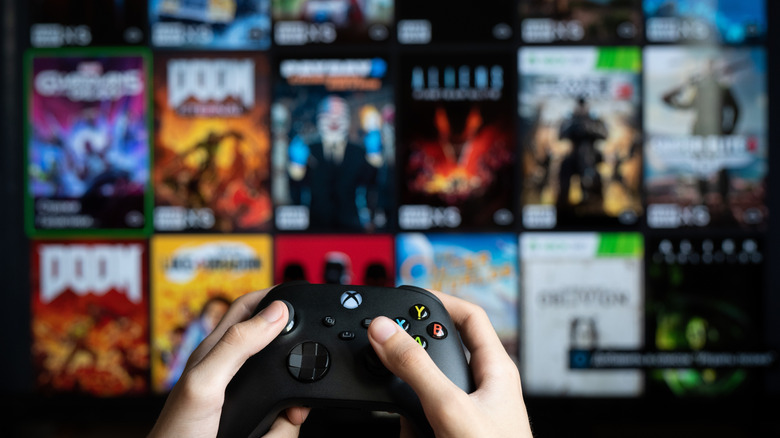 Xbox Series X controller with blurry screen displaying games in background